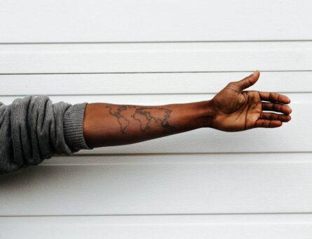 Black skinned person with a world map tattooed on their arm.