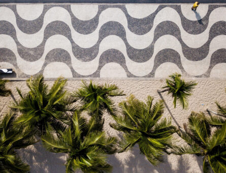 Rio de Janeiro, Brazil - March 29, 2021: Famous mosaic of Copacabana beach sidewalk and palm trees view from the top.